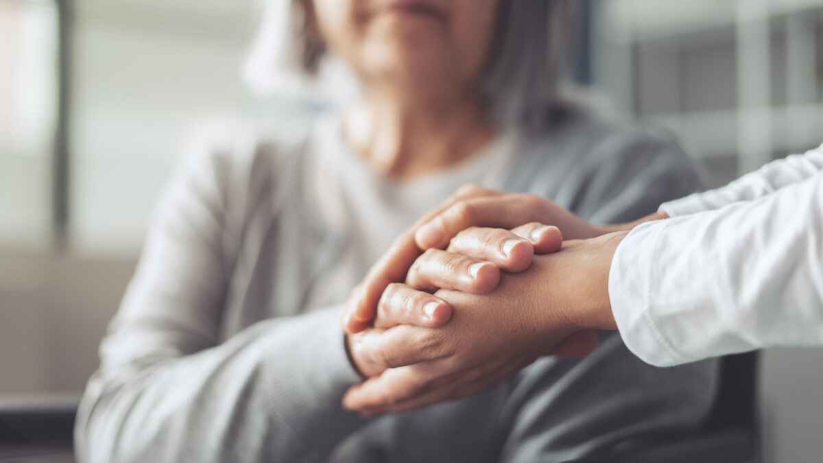 Elderly woman holds doctor's hands
